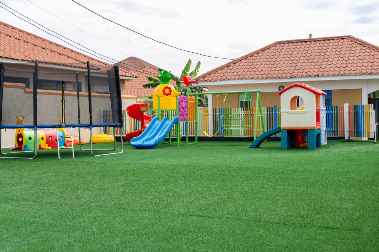 The fenced play garden with slides, a climbing frame and a playhouse