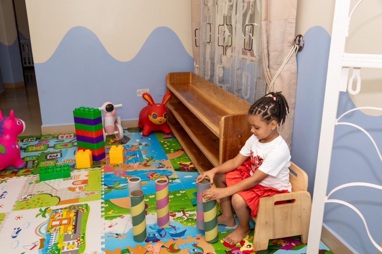 A toddler playing on the soft-play mat with blocks and toys