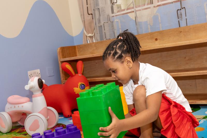 A girl building with large green blocks in the soft-play room