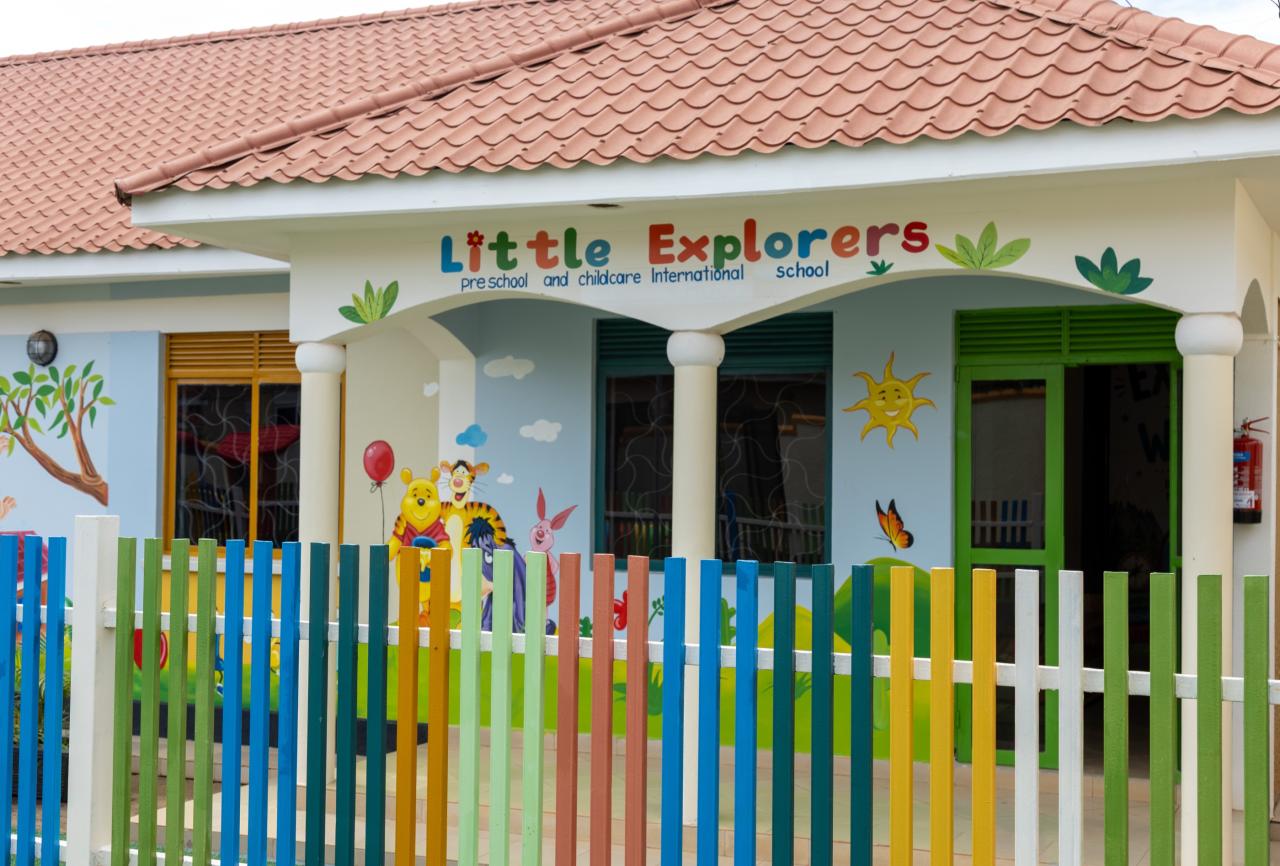 The Little Explorers school building with its name above the door and a rainbow fence in front