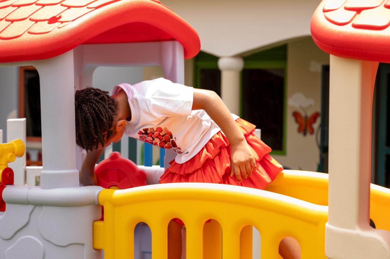 A toddler climbing into the colourful playhouse