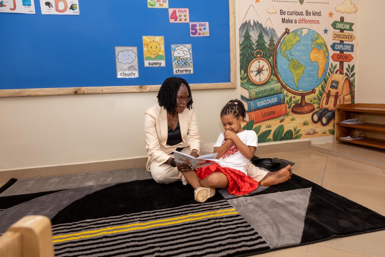 A teacher reading a picture book with a girl on the classroom rug