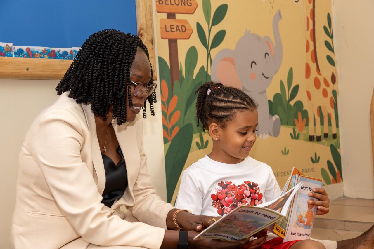 A teacher sharing a picture book with a smiling girl