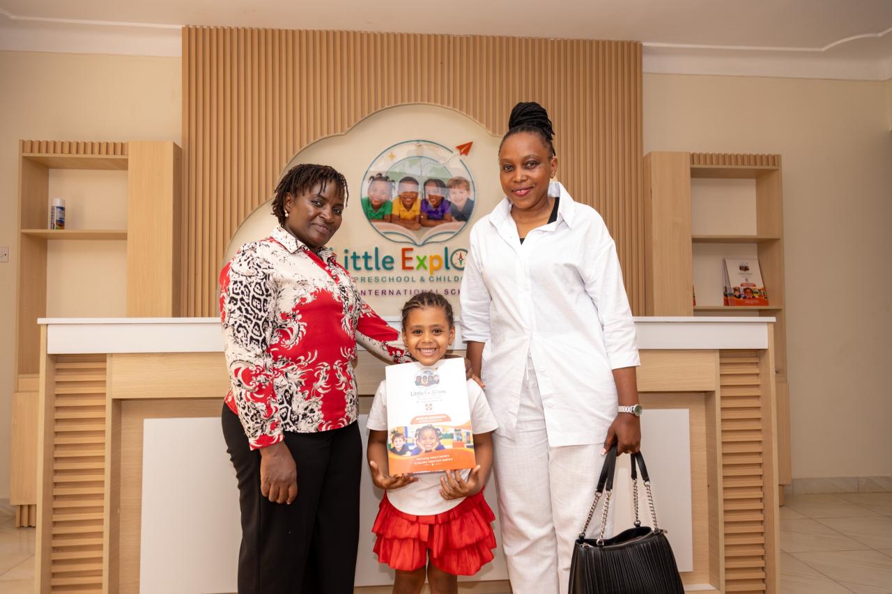 A family and a team member smiling with a child at the Little Explorers reception desk